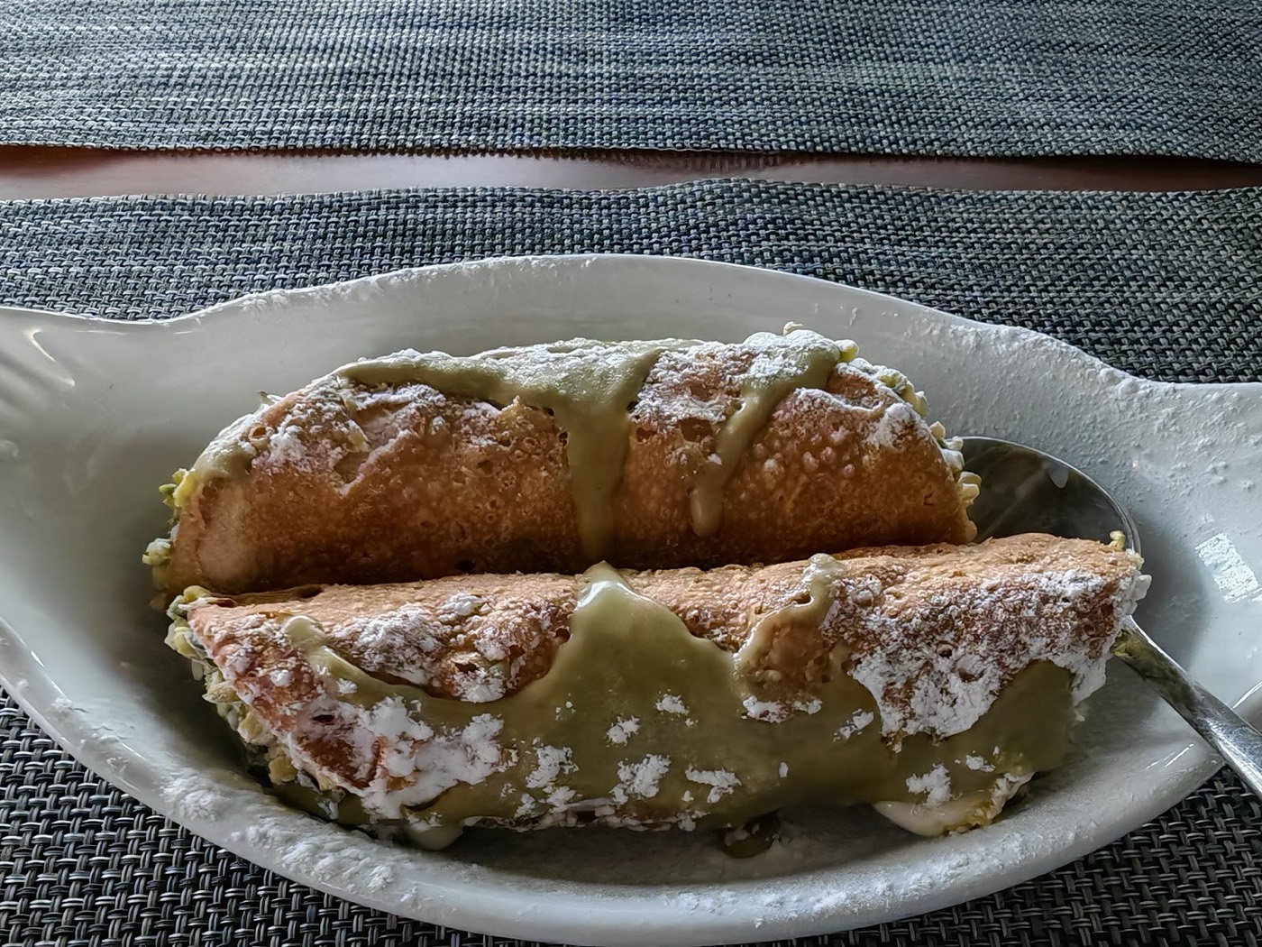 Two large cannoli generously topped with pistachio cream